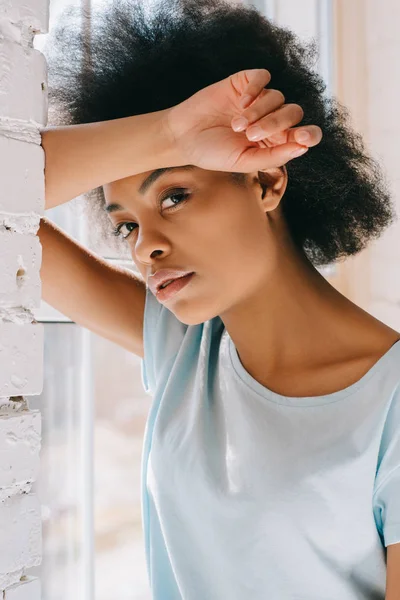 Relajada afroamericana chica apoyada en la pared por ventana - foto de stock