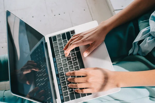 Mulher digitando no teclado do laptop de joelhos — Fotografia de Stock