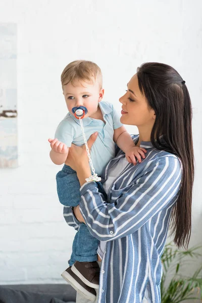 Ritratto della giovane madre e del piccolo bambino con ciuccio a casa — Foto stock