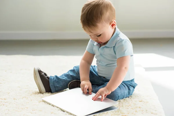 Petit garçon bébé avec ordinateur portable assis sur le sol à la maison — Photo de stock