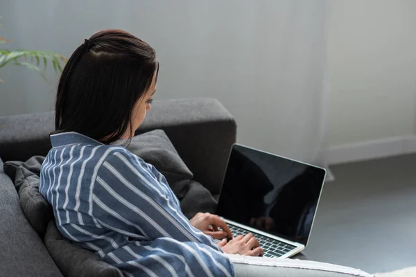 Vue latérale de la femme en utilisant un ordinateur portable avec écran vierge à la maison — Photo de stock