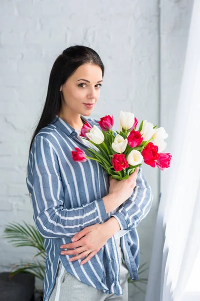 Beautiful smiling woman with bouquet of tulips at home — Stock Photo