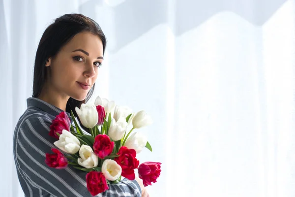 Side view of beautiful woman with bouquet of tulips at home — Stock Photo