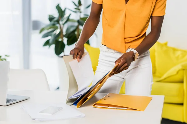 Vue partielle de la femme afro-américaine avec des dossiers travail à distance au bureau à domicile — Photo de stock
