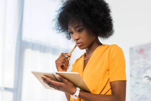 Portrait of thoughtful african american freelancer with notebook at home office — Stock Photo