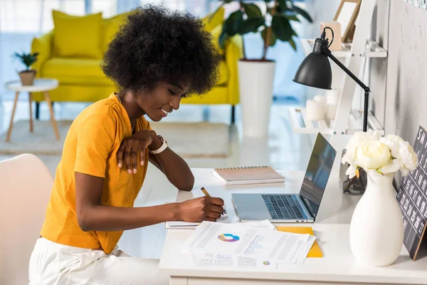 Seitenansicht einer lächelnden afrikanisch-amerikanischen Freiberuflerin, die zu Hause arbeitet — Stockfoto