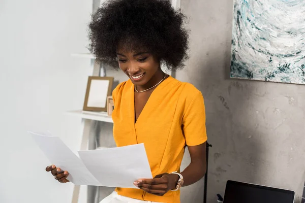 Portrait de souriant afro-américain pigiste avec des papiers au bureau à domicile — Photo de stock
