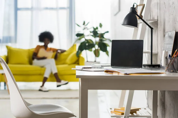 Foyer sélectif de l'ordinateur portable sur la table et afro-américaine pigiste au bureau à domicile — Photo de stock