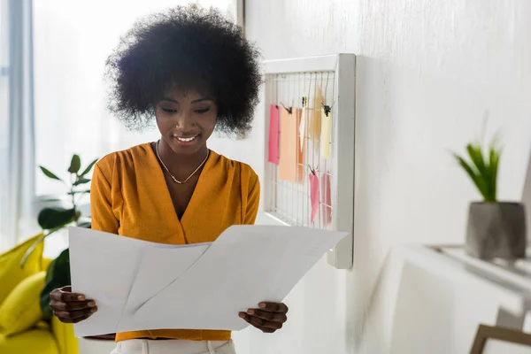 Портрет улыбающегося африканского фрилансера с бумагами в домашнем офисе — стоковое фото