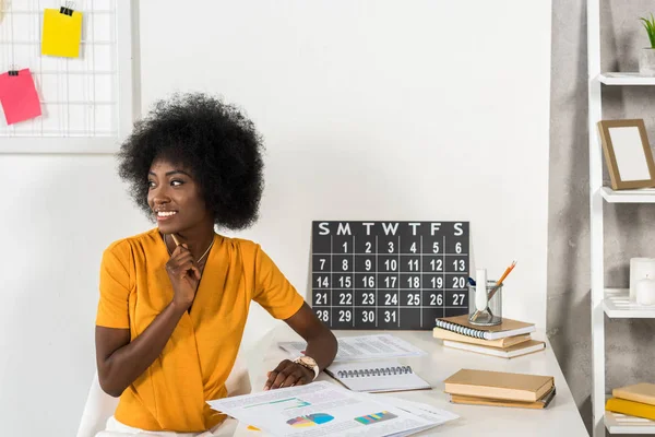 Sorrindo freelancer afro-americano olhando para longe no local de trabalho em casa escritório — Fotografia de Stock