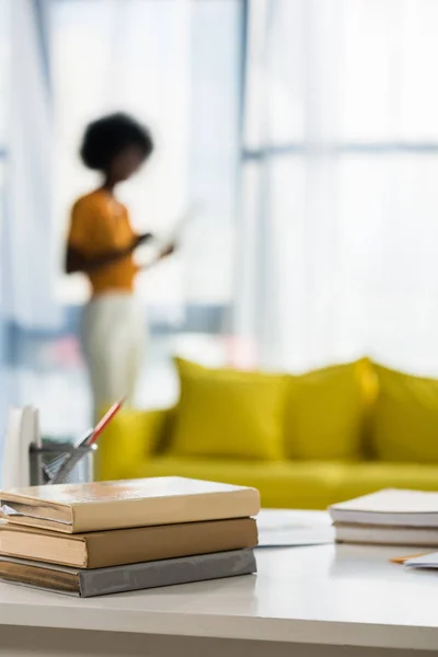 Focus selettivo di libri sul posto di lavoro e freelance afroamericano su sfondo a casa ufficio — Foto stock