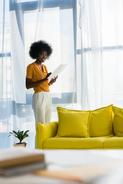Freelancer afro-americano sorridente com papéis em home office — Fotografia de Stock