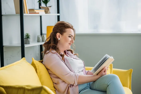 Seitenansicht attraktive Frau liest Buch auf Sofa zu Hause — Stockfoto