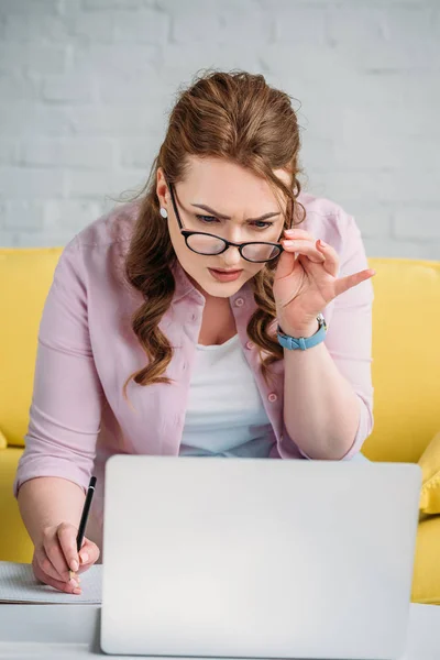 Confused woman looking at laptop at home — Stock Photo