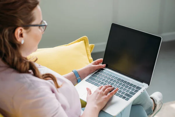 Side view of freelancer sitting with laptop on sofa at home — Stock Photo