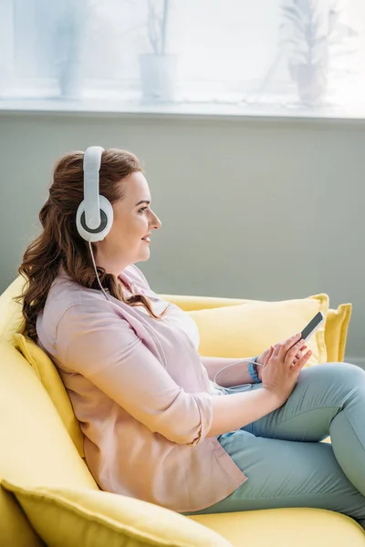 Vue latérale de belle femme écoutant de la musique sur le canapé à la maison — Photo de stock