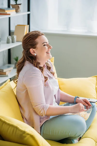 Side view of beautiful woman watching comedy movie with popcorn at home — Stock Photo