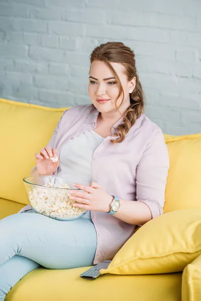 Приваблива жінка дивиться фільм з попкорном вдома — стокове фото