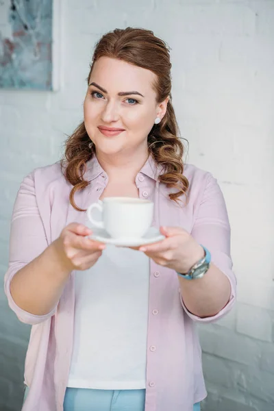 Belle femme montrant tasse de café à la maison — Photo de stock