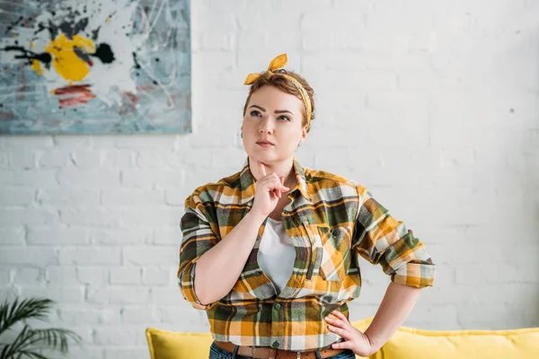 Portrait of beautiful pensive woman in checkered shirt and headband at home — Stock Photo