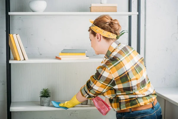 Seitenansicht der schönen Frau, die zu Hause Regale staubt — Stockfoto