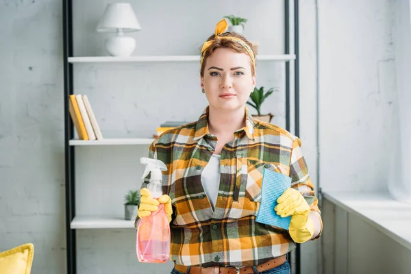 Schöne Frau zeigt Sprühflasche und Lappen zum Putzen zu Hause — Stockfoto
