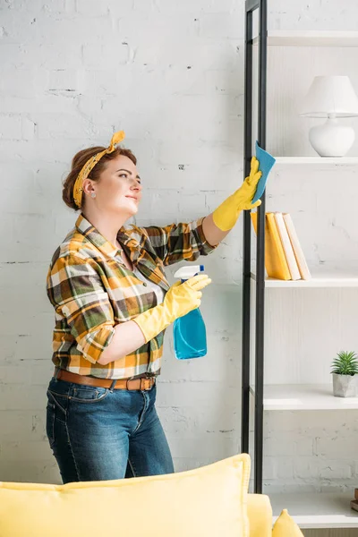 Belle femme époussetant étagères à la maison — Photo de stock