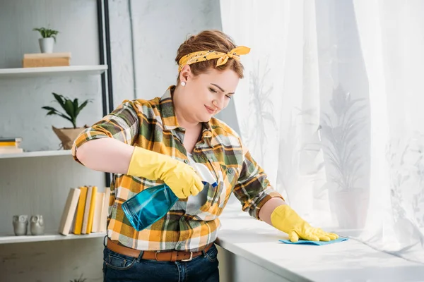 Belle femme époussetant rebord de fenêtre à la maison — Photo de stock