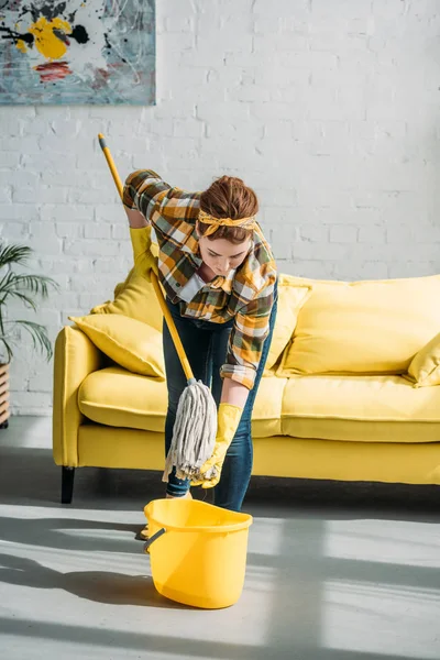 Beautiful woman wringing out rag on mop at home — Stock Photo