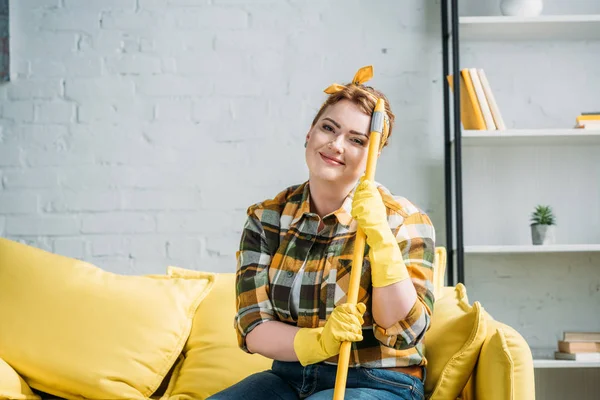 Schöne Frau sitzt zu Hause auf Sofa mit Wischmopp — Stockfoto