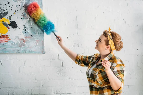 Bela mulher espanando tinta na parede em casa — Fotografia de Stock