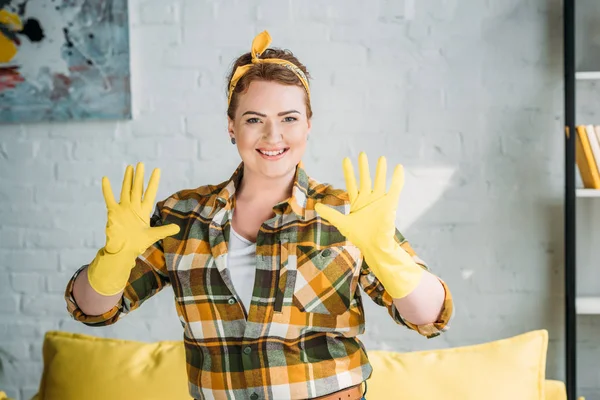 Красива жінка, що показує руки в гумових рукавичках для прибирання вдома — стокове фото