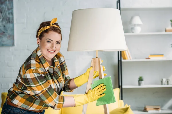 Hermosa mujer lámpara de polvo con trapo en casa - foto de stock