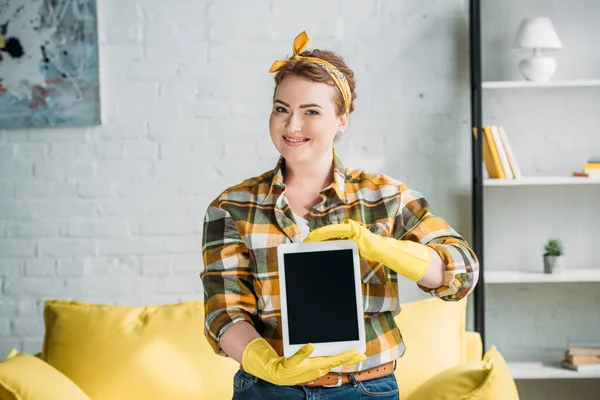 Schöne Frau in Putzhandschuhen zeigt Tablet zu Hause — Stockfoto