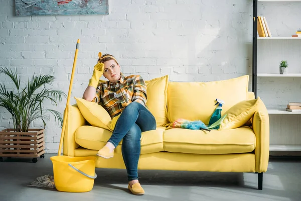 Втомлена красива жінка сидить на дивані після прибирання вдома — стокове фото