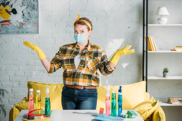 Belle femme montrant les mains près de la table avec des fournitures de nettoyage à la maison — Photo de stock