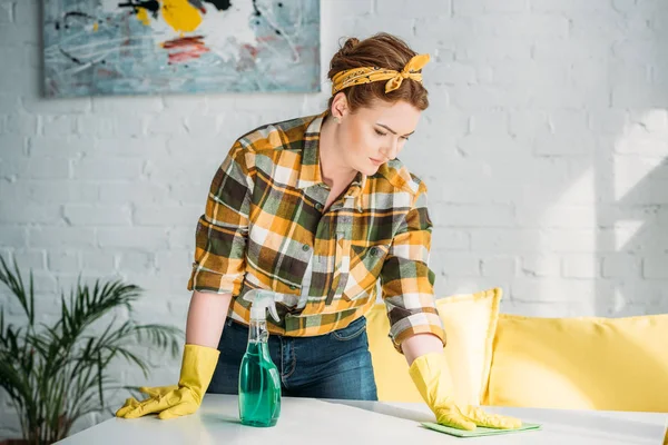 Красивая женщина убирает пыль со стола дома — стоковое фото