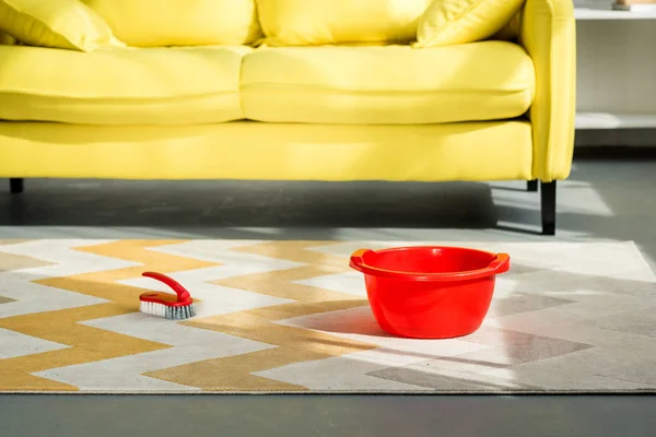 Cubo rojo y cepillo de limpieza en la alfombra en el suelo - foto de stock