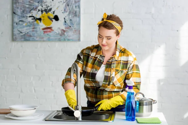 Attractive woman washing frying pan in kitchen — Stock Photo