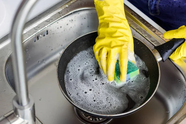 Imagem cortada de mulher que lava a panela de ato de fritar na cozinha — Fotografia de Stock