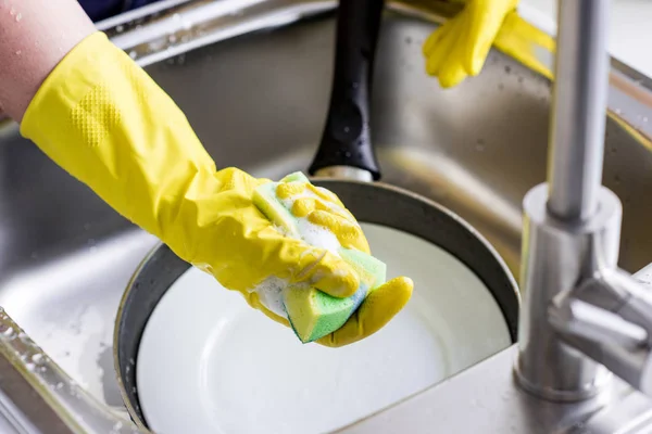 Immagine ritagliata della donna che lava i piatti e tiene la spugna di lavaggio in cucina — Foto stock