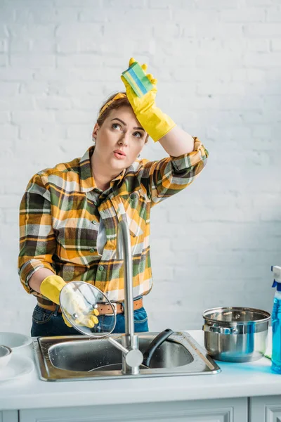 Schöne müde Frau spült Geschirr in der Küche — Stockfoto