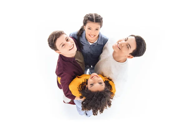 Вид зверху усміхнених мультикультурних підлітків, що обіймають один одного ізольовано на білому — стокове фото