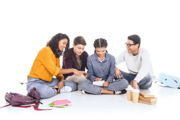 Estudiantes interraciales haciendo tareas juntos aislados en blanco - foto de stock