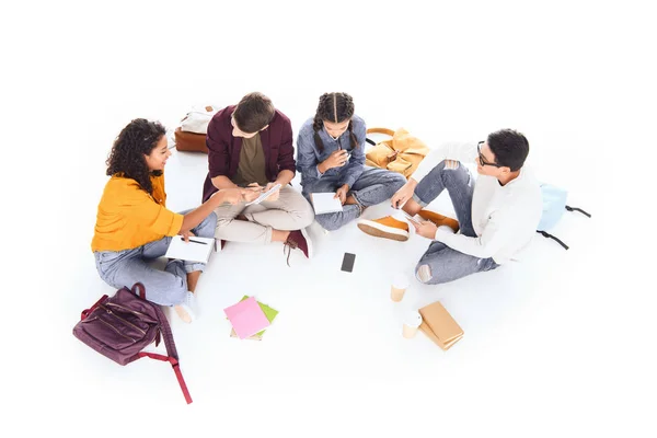 Vista de ángulo alto de los estudiantes multirraciales que hacen la tarea juntos aislados en blanco - foto de stock