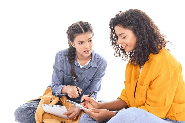 Retrato de estudiantes multiétnicos haciendo tareas juntos aislados en blanco - foto de stock