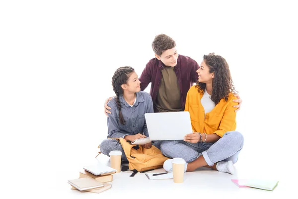 Adolescentes multiculturales con portátil juntos aislados en blanco - foto de stock