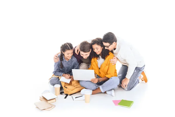 Estudiantes multiétnicos sonrientes usando el ordenador portátil juntos aislados en blanco - foto de stock