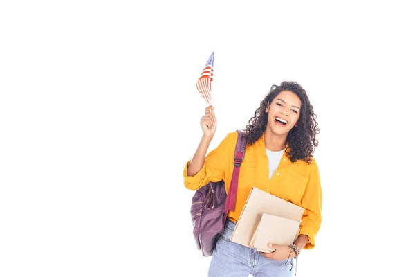 Retrato de estudiante afroamericano feliz con bandera americana, mochila y libros aislados en blanco - foto de stock