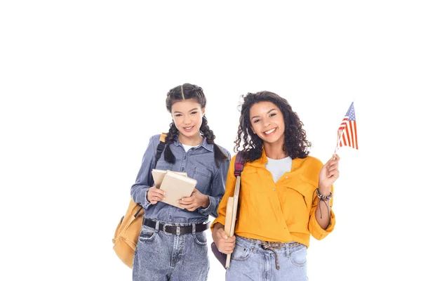 Портрет усміхнених міжрасових студентів з рюкзаками, книгами та американським прапором ізольовано на білому — стокове фото